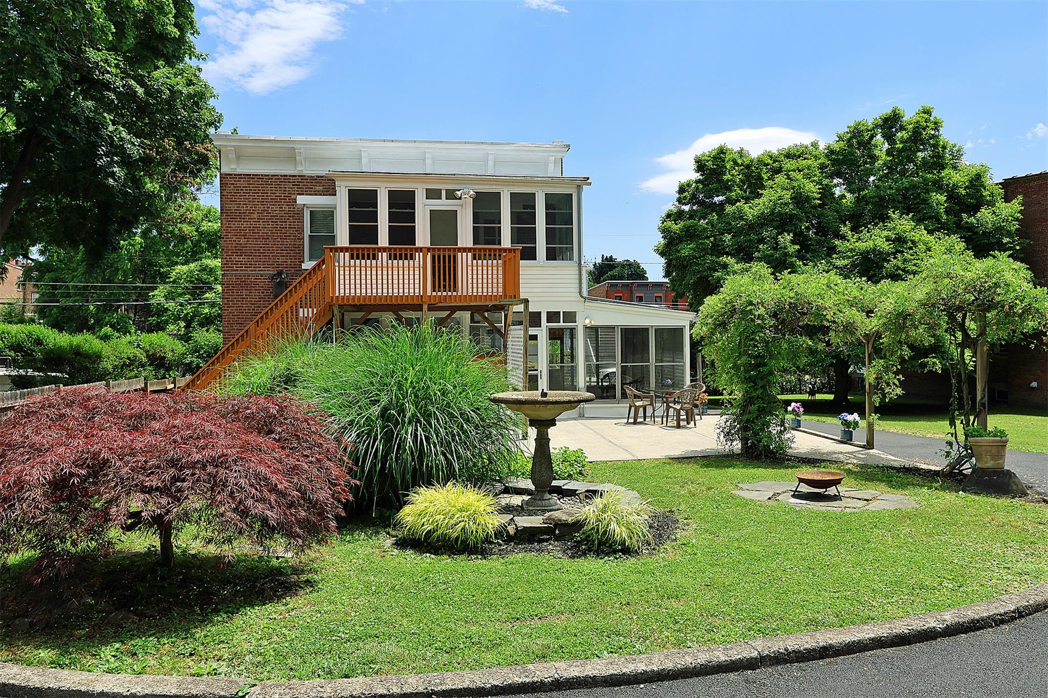 Back of property featuring a wooden deck, a patio area, and a yard