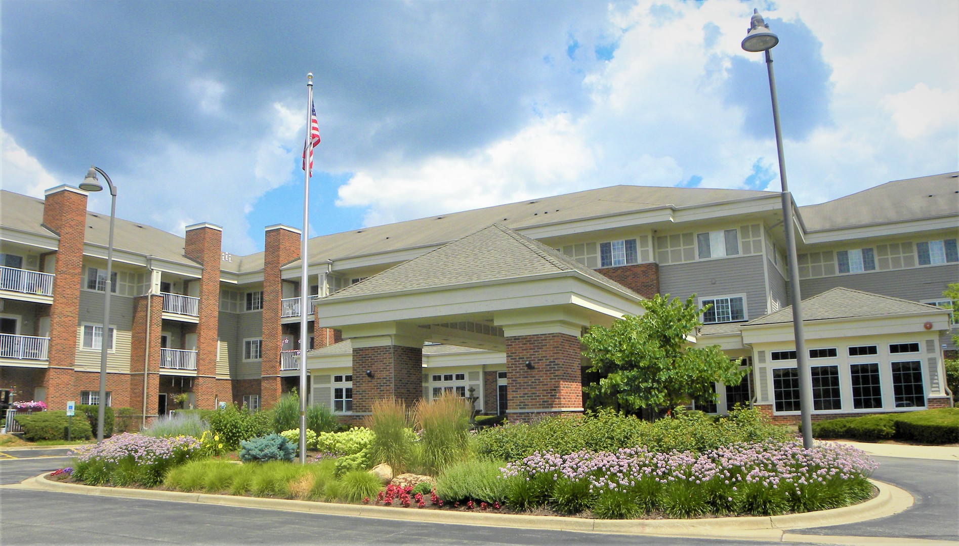 a front view of a multi story residential apartment building with yard and traffic signal