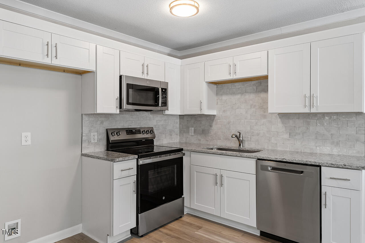 a kitchen with white cabinets and stainless steel appliances