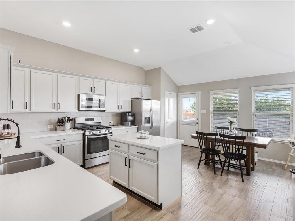 a kitchen with stainless steel appliances a white table chairs and a stove