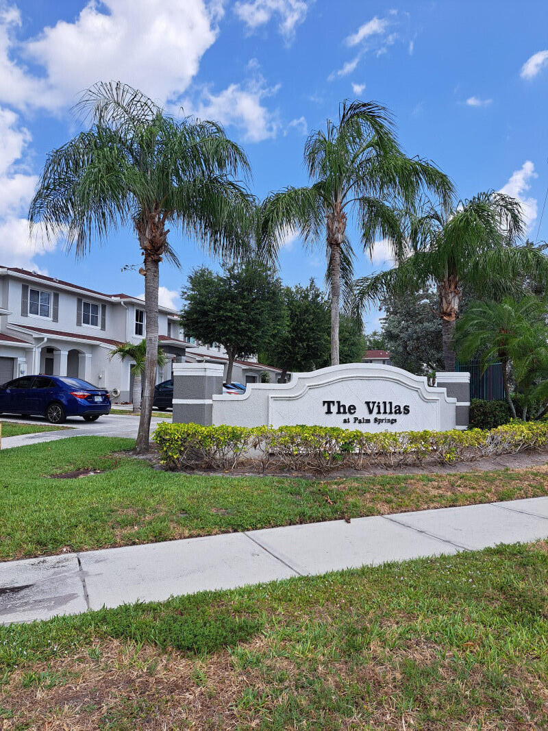 a view of a house with a yard and palm trees