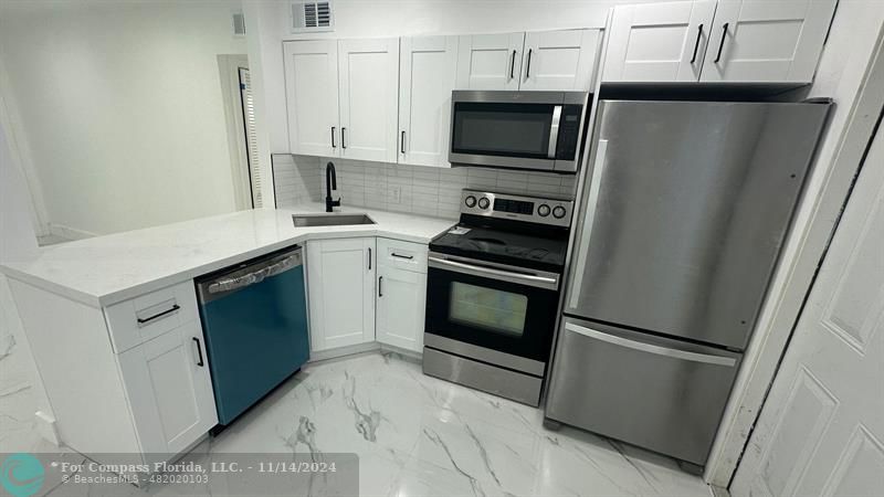 a kitchen with stainless steel appliances a stove microwave and refrigerator