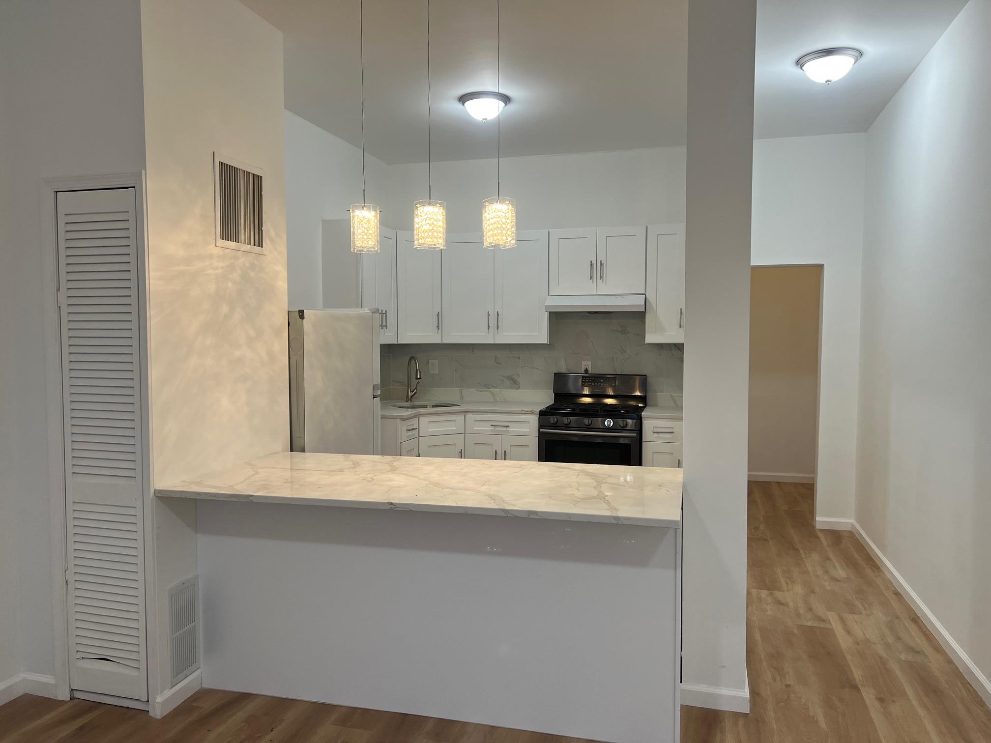 Kitchen featuring backsplash, hanging light fixtures, sink, appliances with stainless steel finishes, and white cabinetry