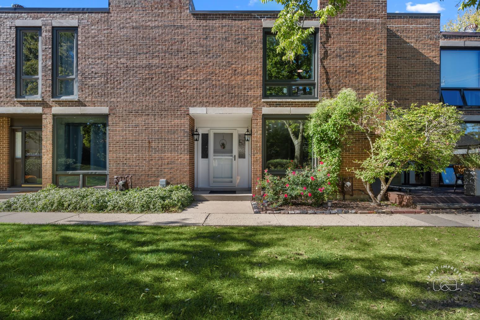 a view of a brick house with a yard and plants