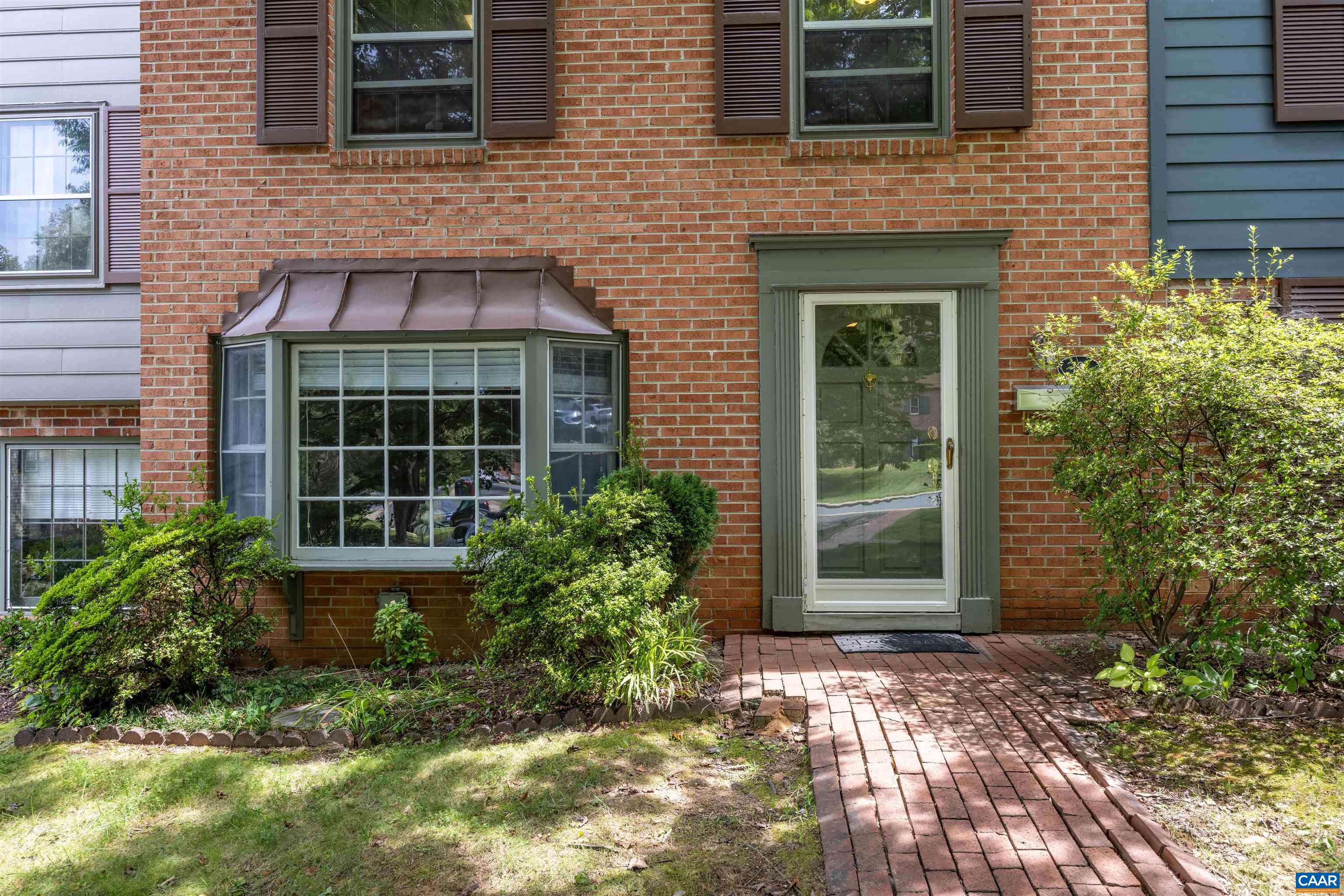 a view of a brick house with plants and large windows