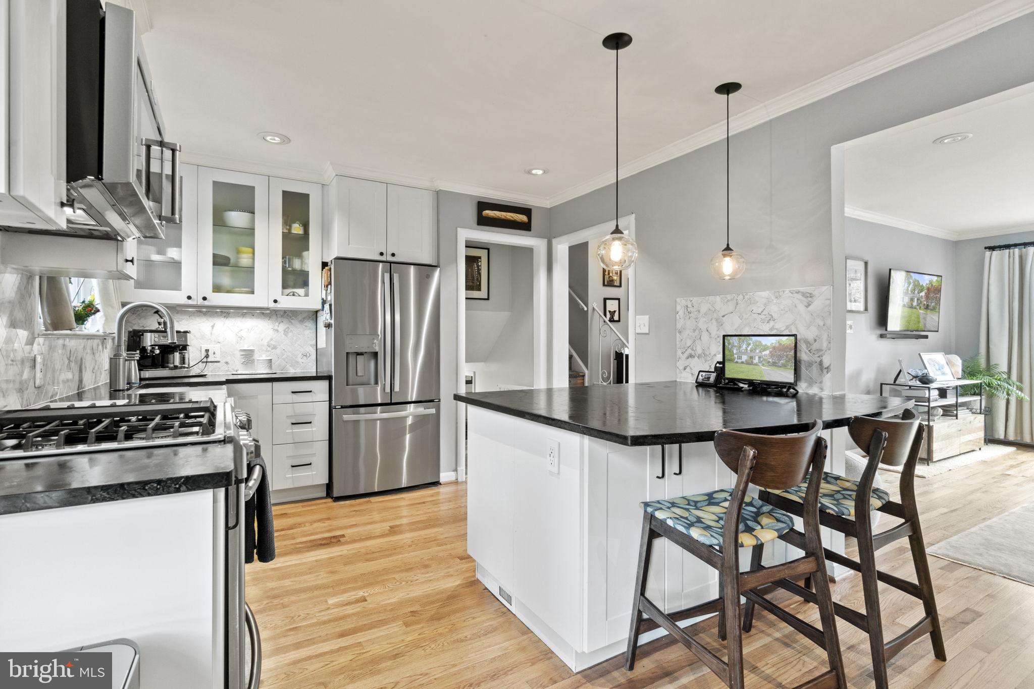 a kitchen with stainless steel appliances a refrigerator a stove a sink and chairs