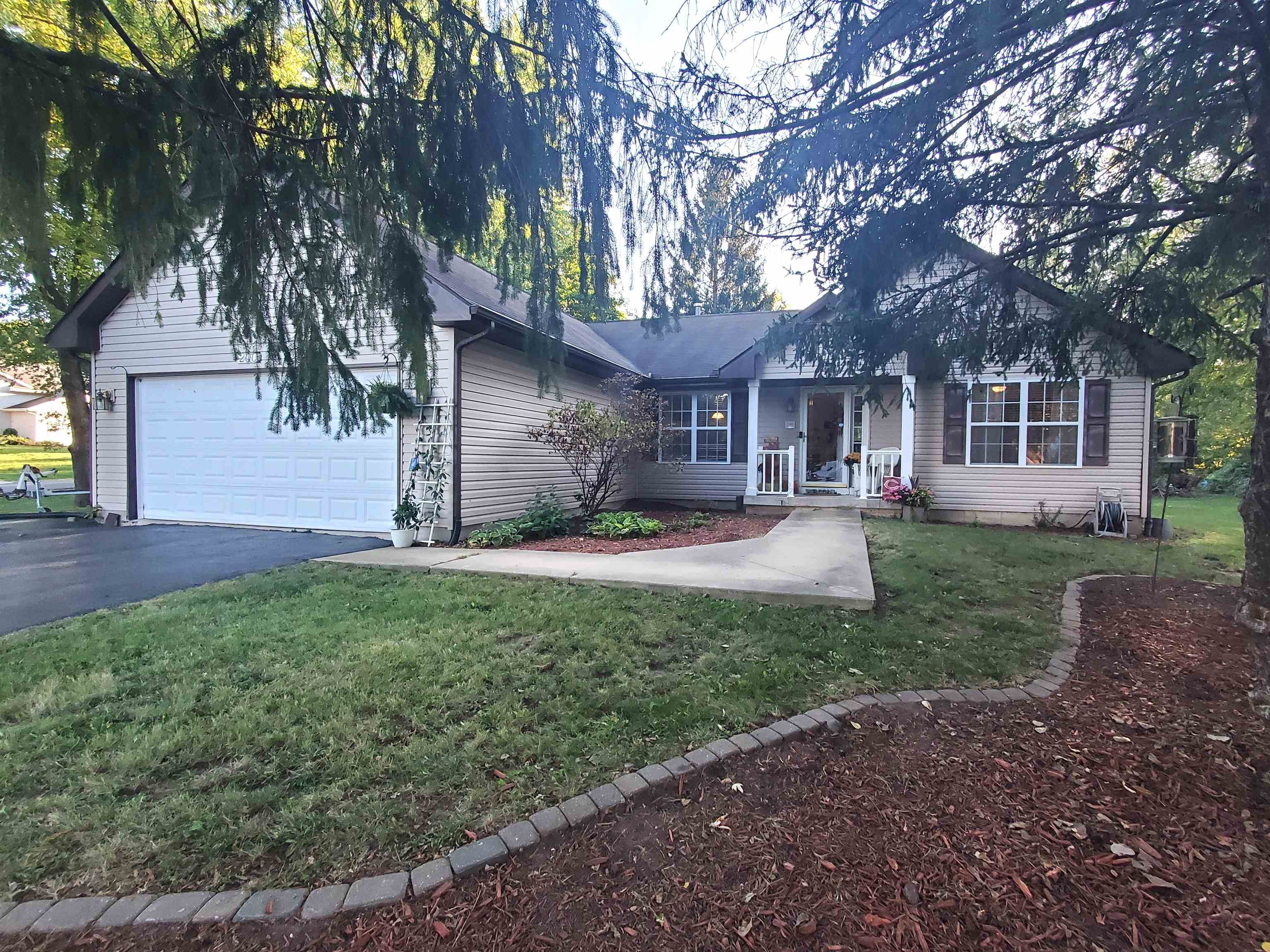 a front view of a house with a garden and trees