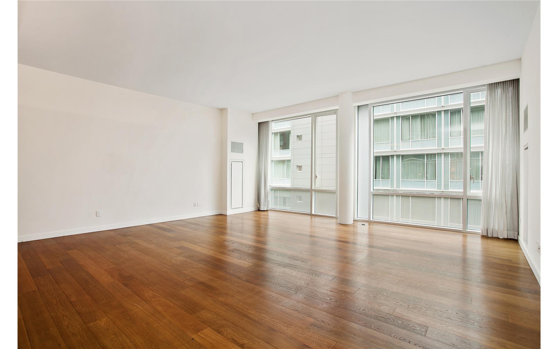 a view of an empty room with wooden floor and windows