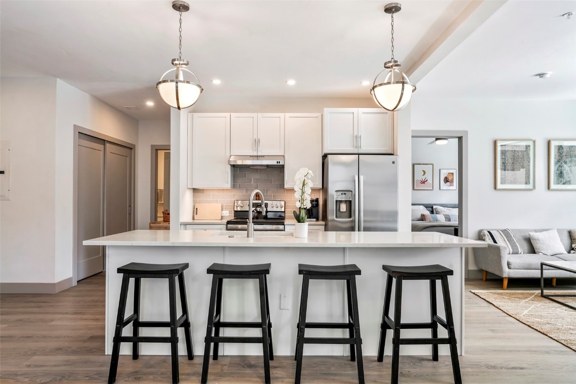 a kitchen with stainless steel appliances granite countertop a dining table and chairs