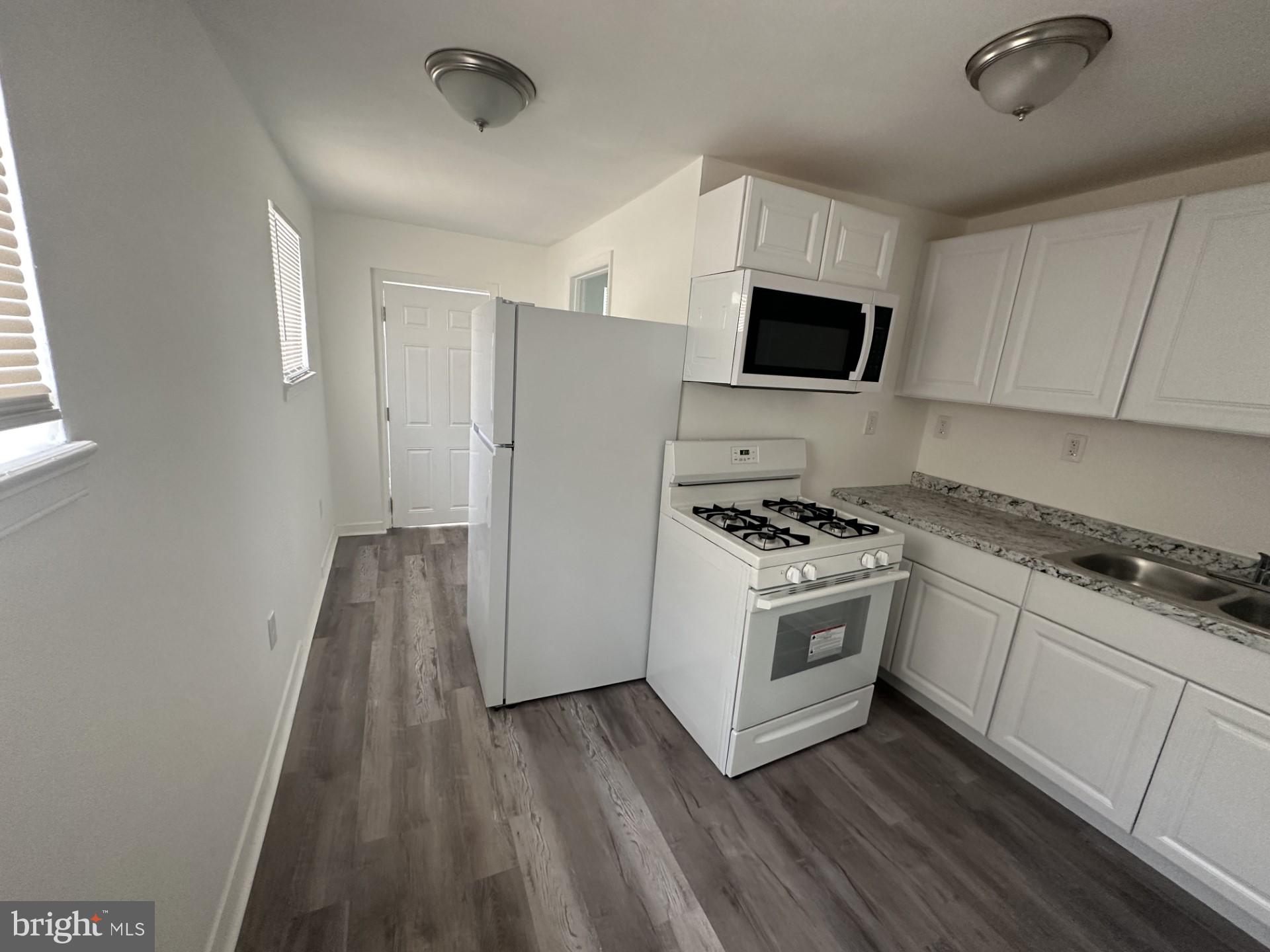 a kitchen with cabinets stainless steel appliances and wooden floor