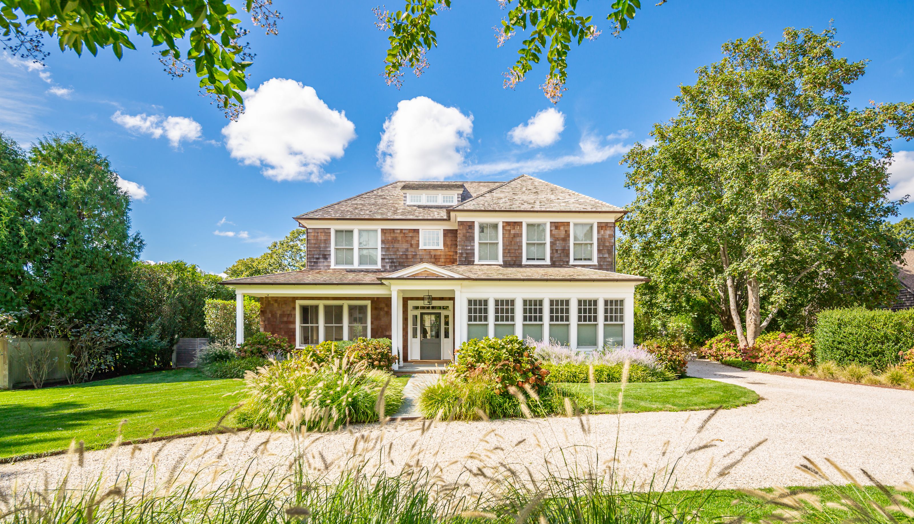 a front view of a house with a yard and potted plants