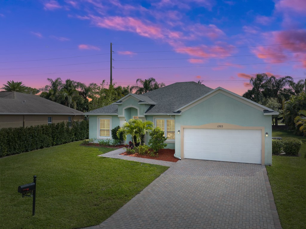 a front view of a house with a yard and potted plants