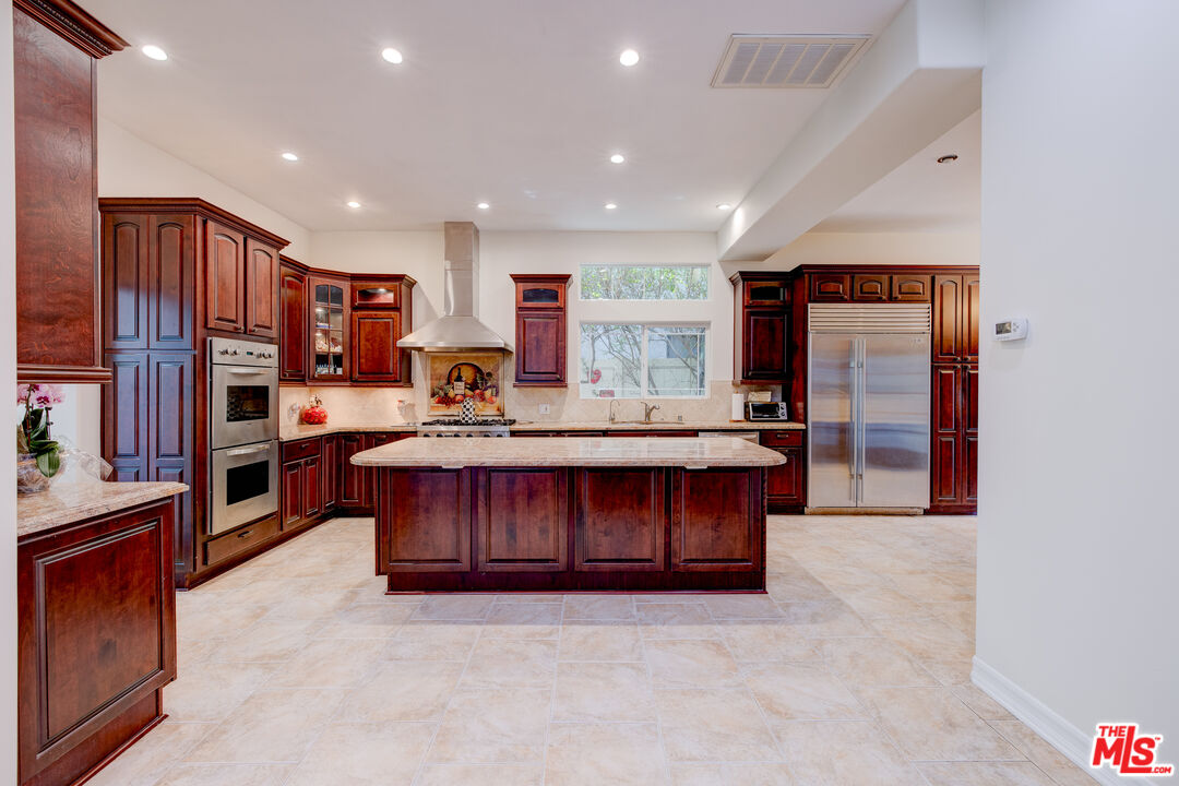 a kitchen with stainless steel appliances granite countertop a stove refrigerator sink and cabinets