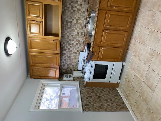 Kitchen with decorative backsplash, light tile patterned floors, sink, and white range with gas cooktop