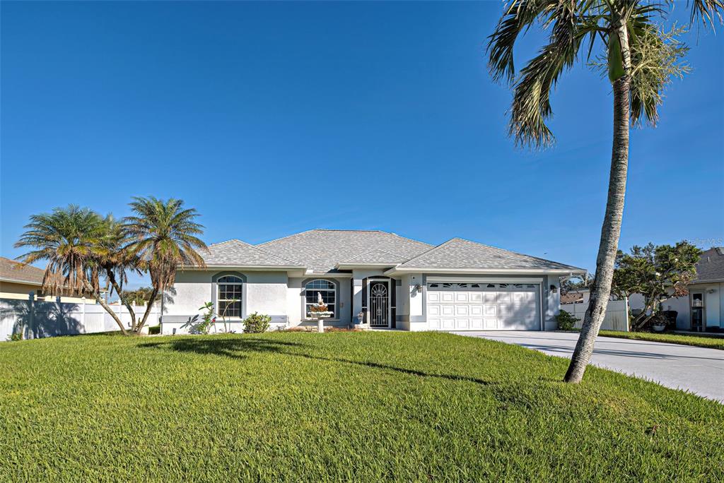 a view of a white house with a big yard and palm trees