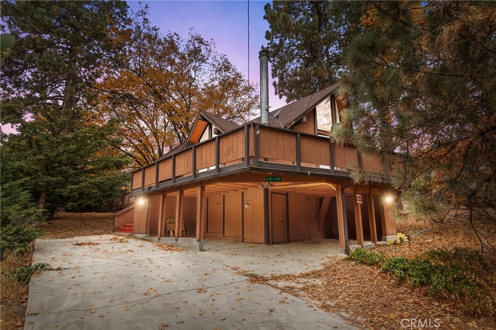 a view of a house with large trees next to a road