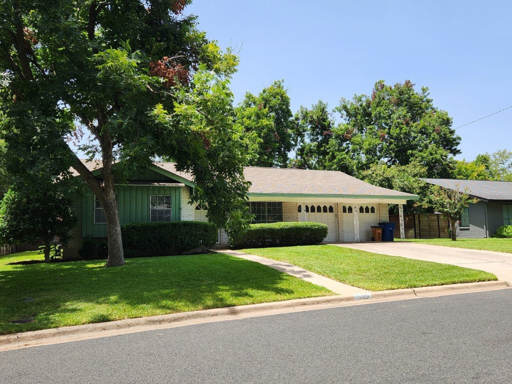 a view of a house with a yard and large trees