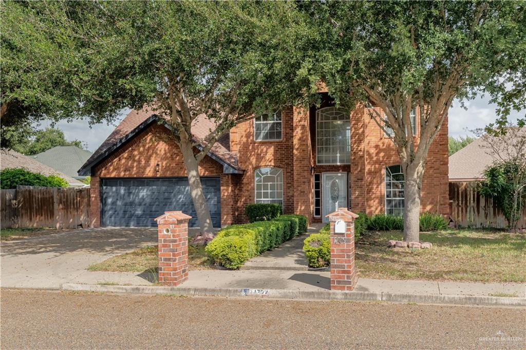 a front view of a house with a yard and tree s