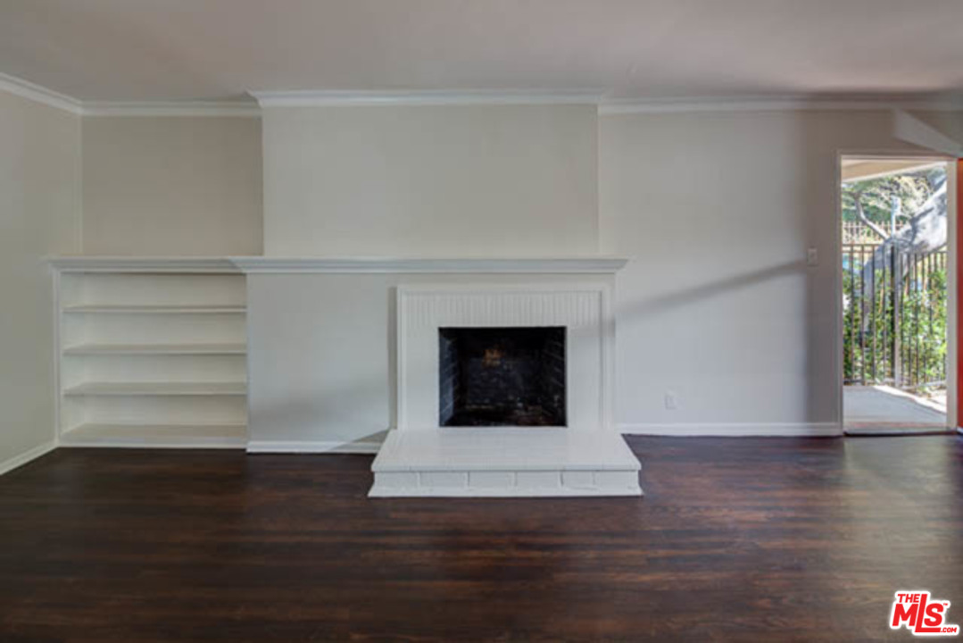 a view of an empty room with wooden floor and a fireplace