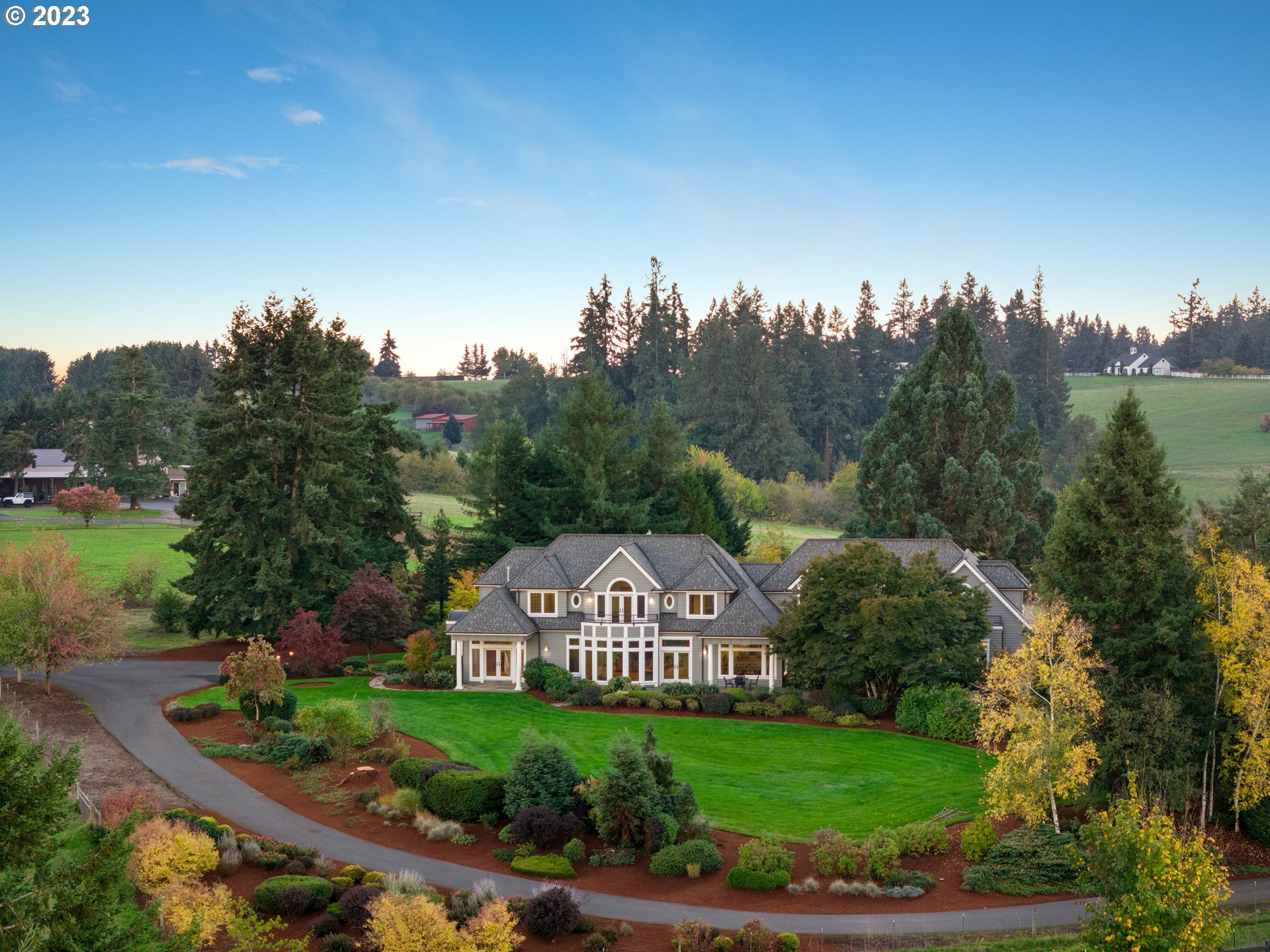 a view of a big house with a big yard and large trees