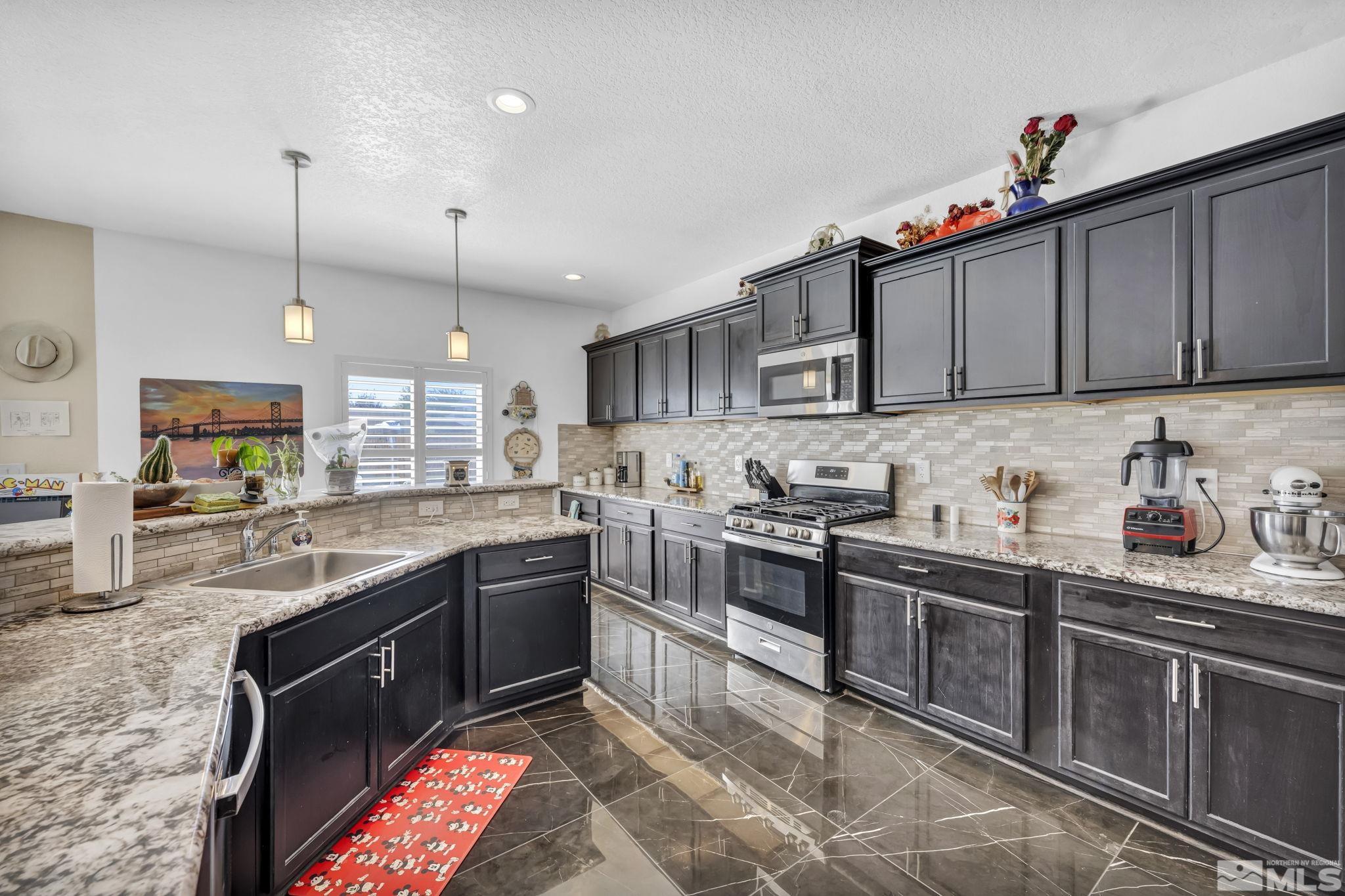 a kitchen with stainless steel appliances granite countertop a sink a stove and a refrigerator