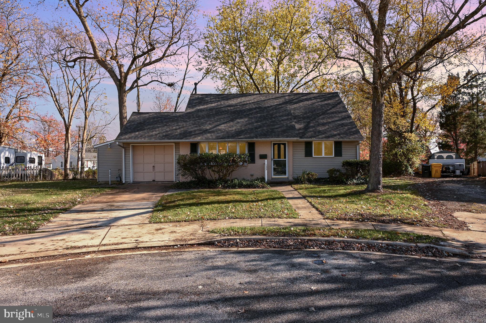 a view of a white house with a large tree next to a yard