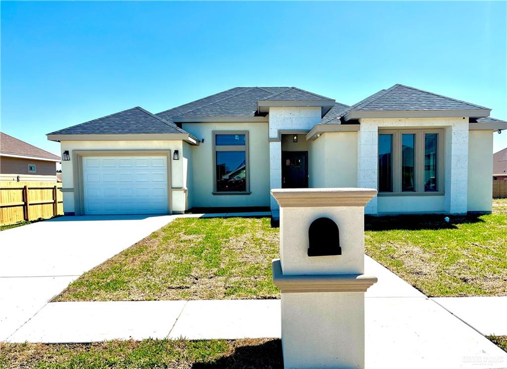 View of front of property featuring a front lawn and a garage