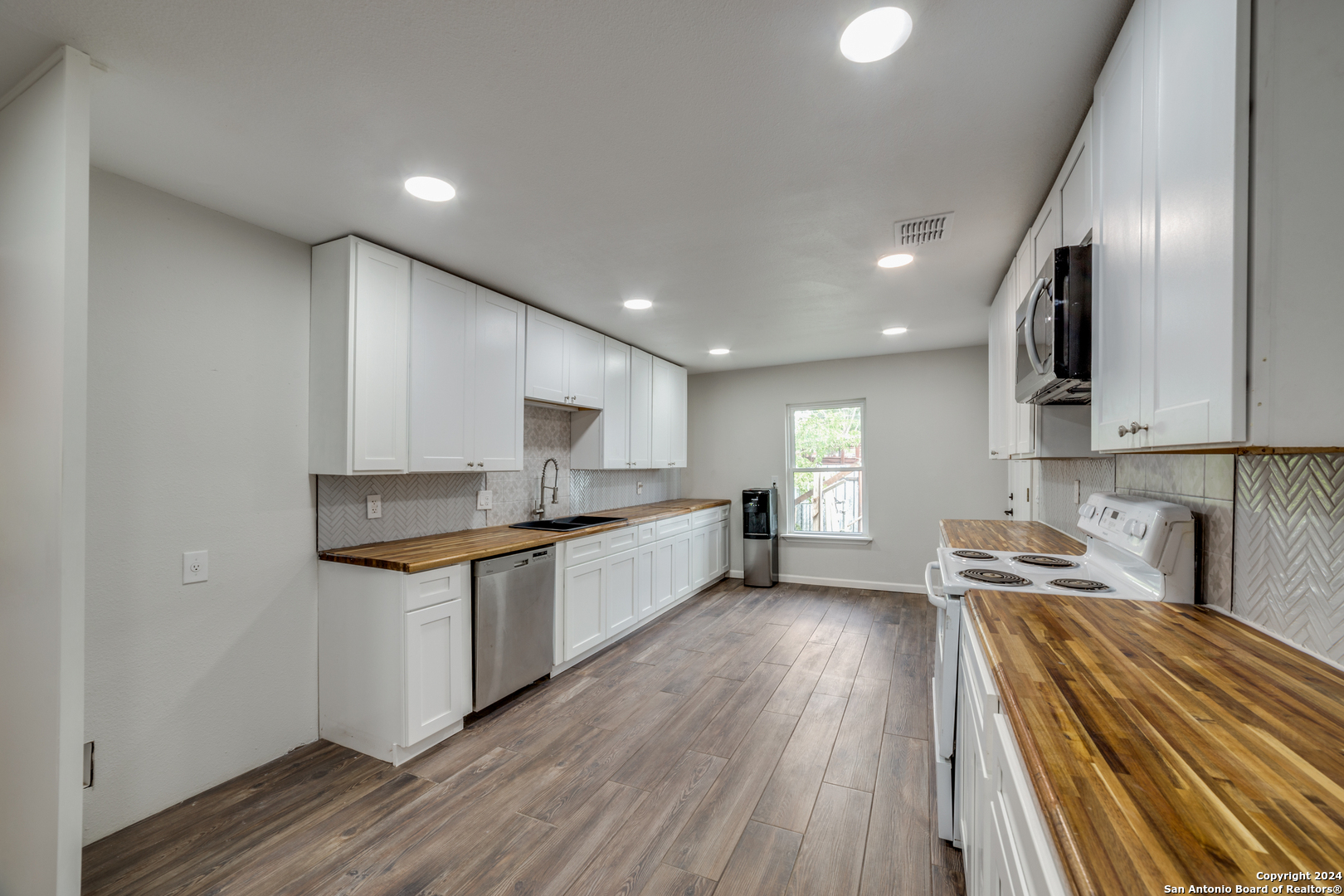 a large kitchen with stainless steel appliances granite countertop a lot of counter space and wooden floors