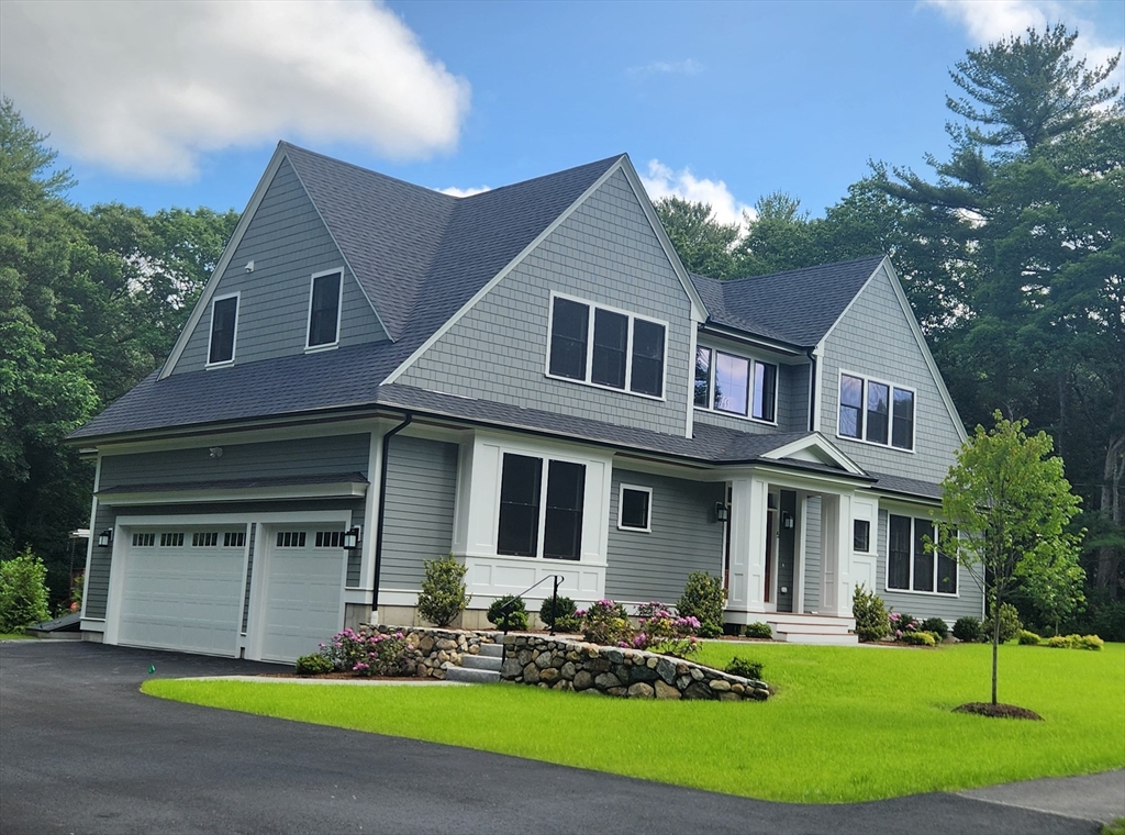 a front view of a house with garden and trees