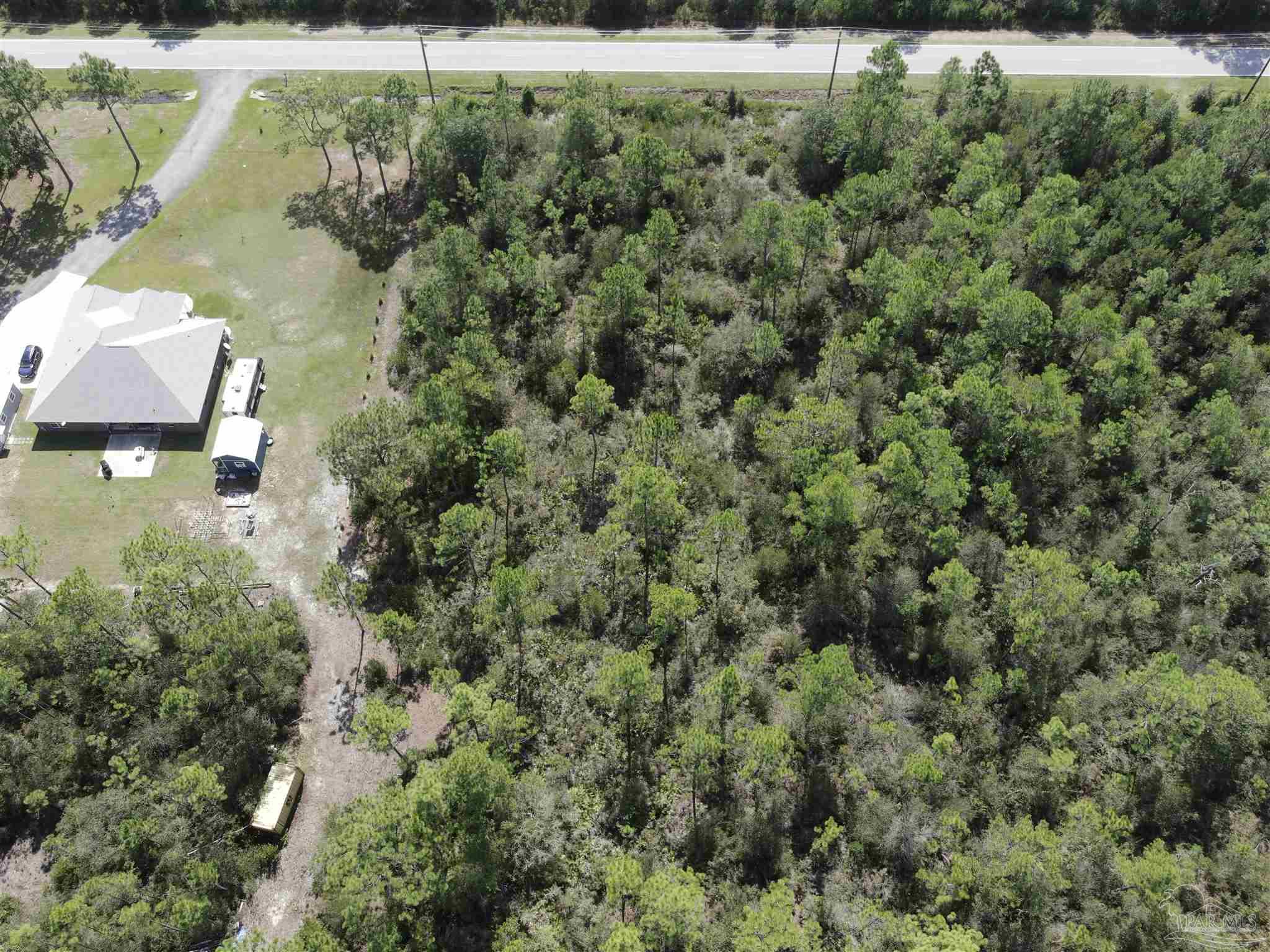 an aerial view of residential houses with outdoor space and trees