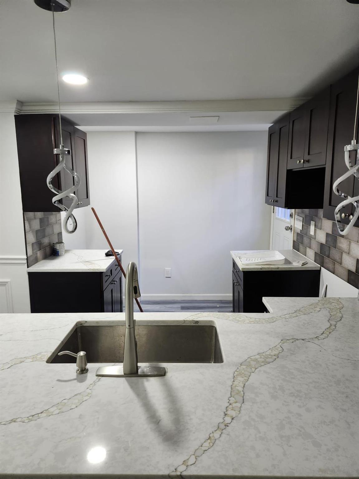 Kitchen featuring decorative backsplash, a center island, light stone countertops, and sink