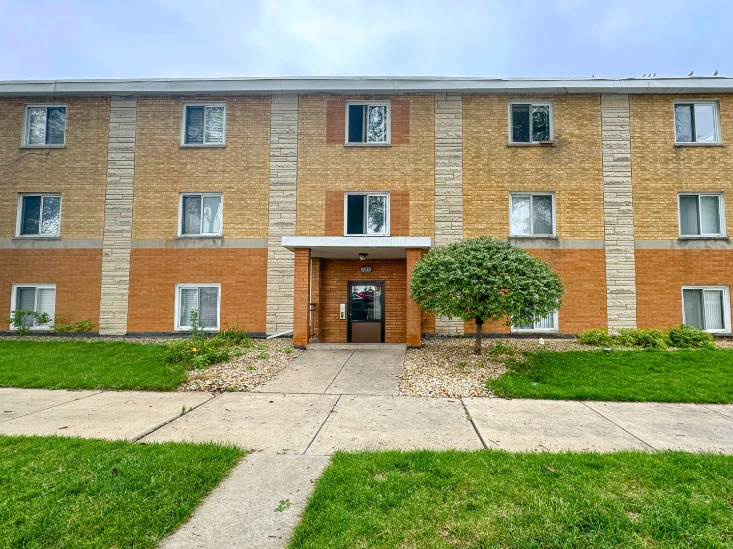 a front view of a house with yard and parking