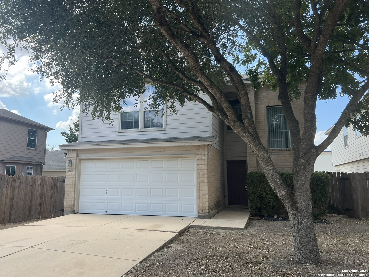 a front view of a house with a tree