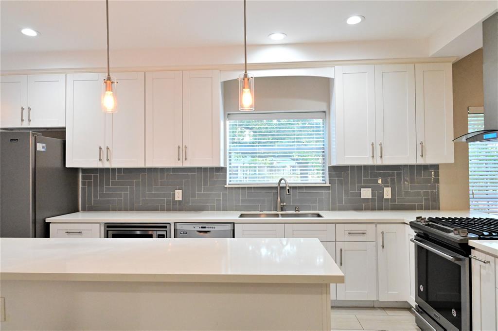 a kitchen with stainless steel appliances granite countertop a sink a stove and a refrigerator