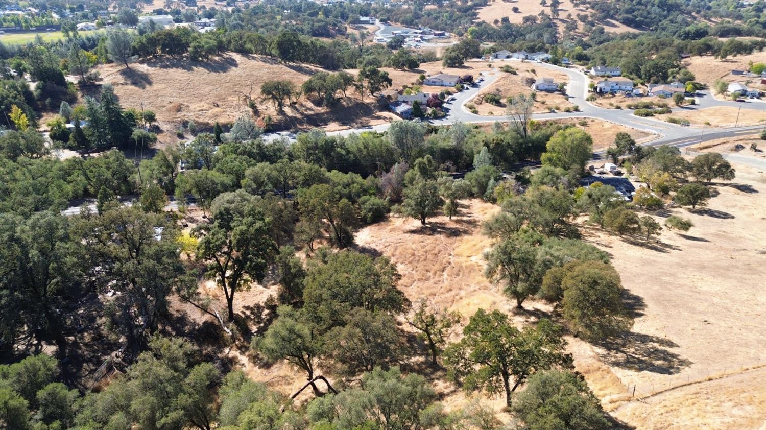 an aerial view of residential houses with outdoor space and trees