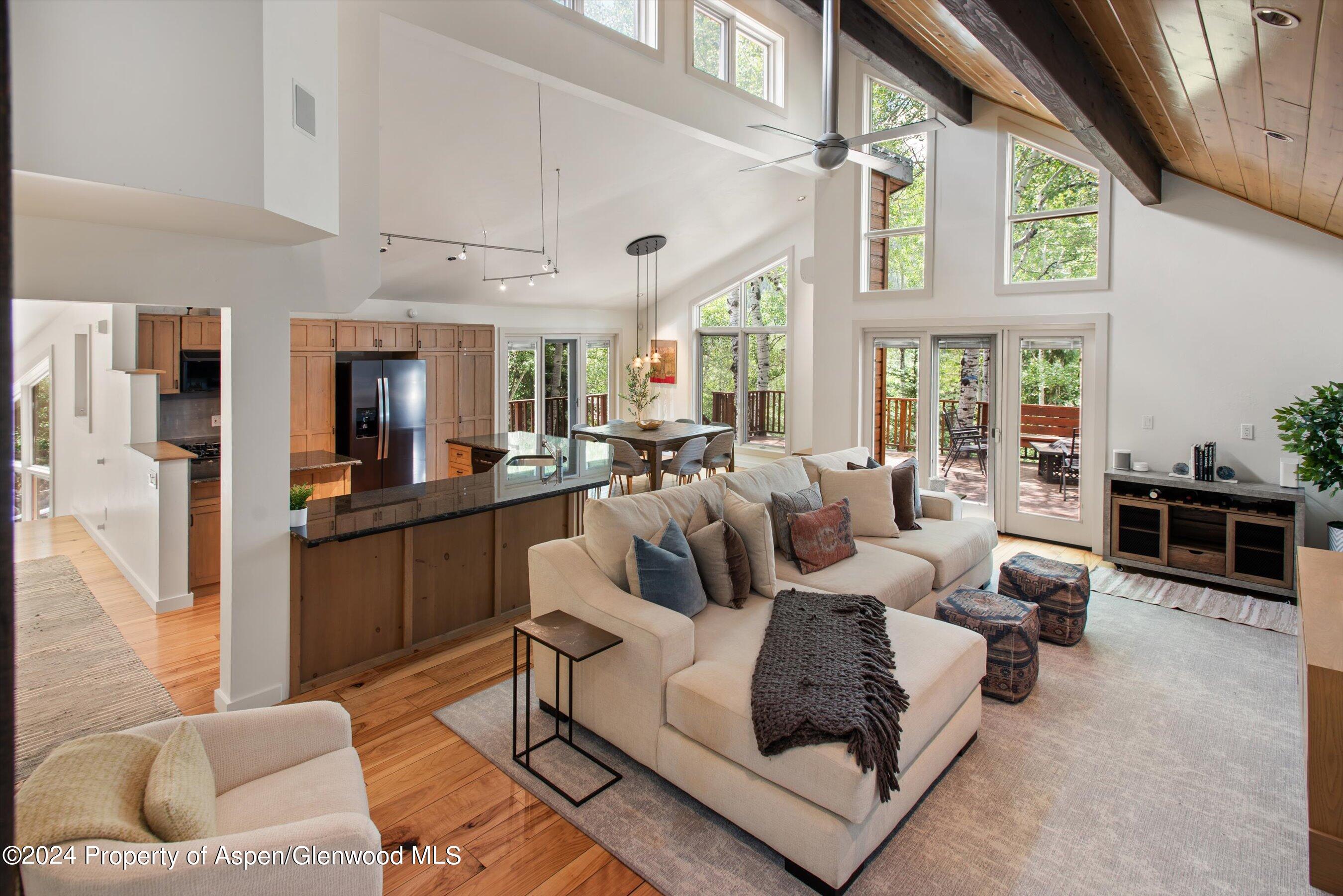 a living room with furniture large window and kitchen view