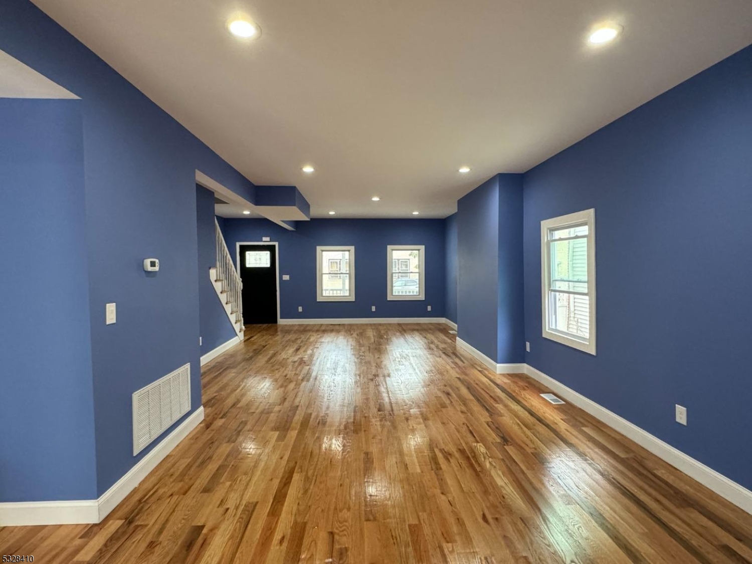 a view of empty room with wooden floor and fan