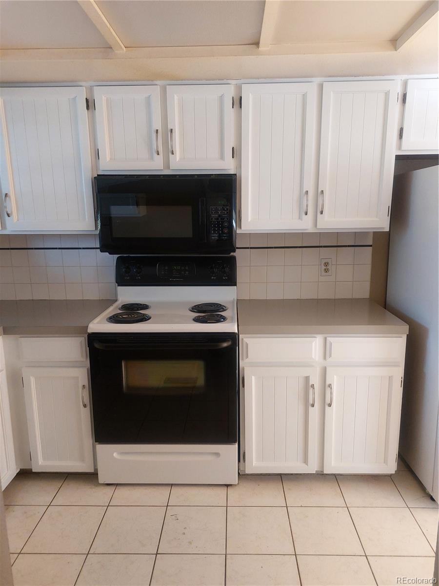 a kitchen with white cabinets and appliances