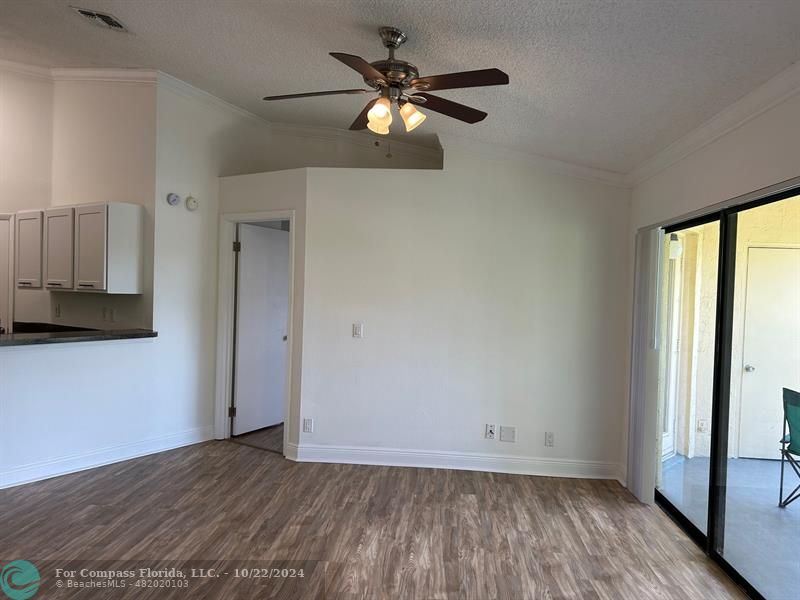 a view of an empty room with window a ceiling fan and wooden floor