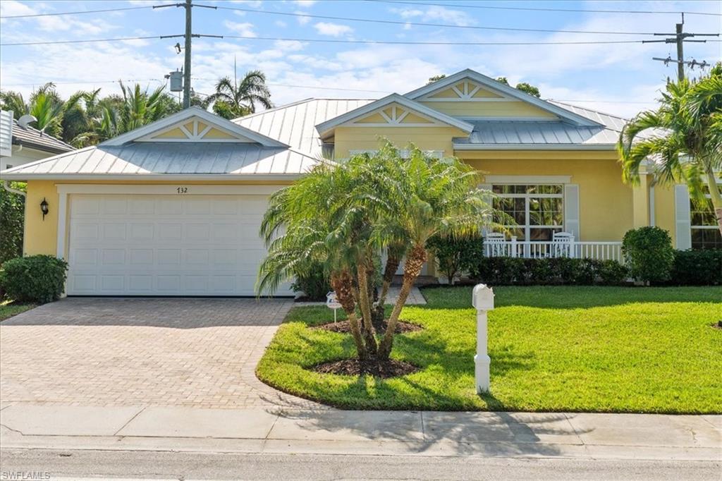 View of front of home with a porch, a garage, and a front lawn