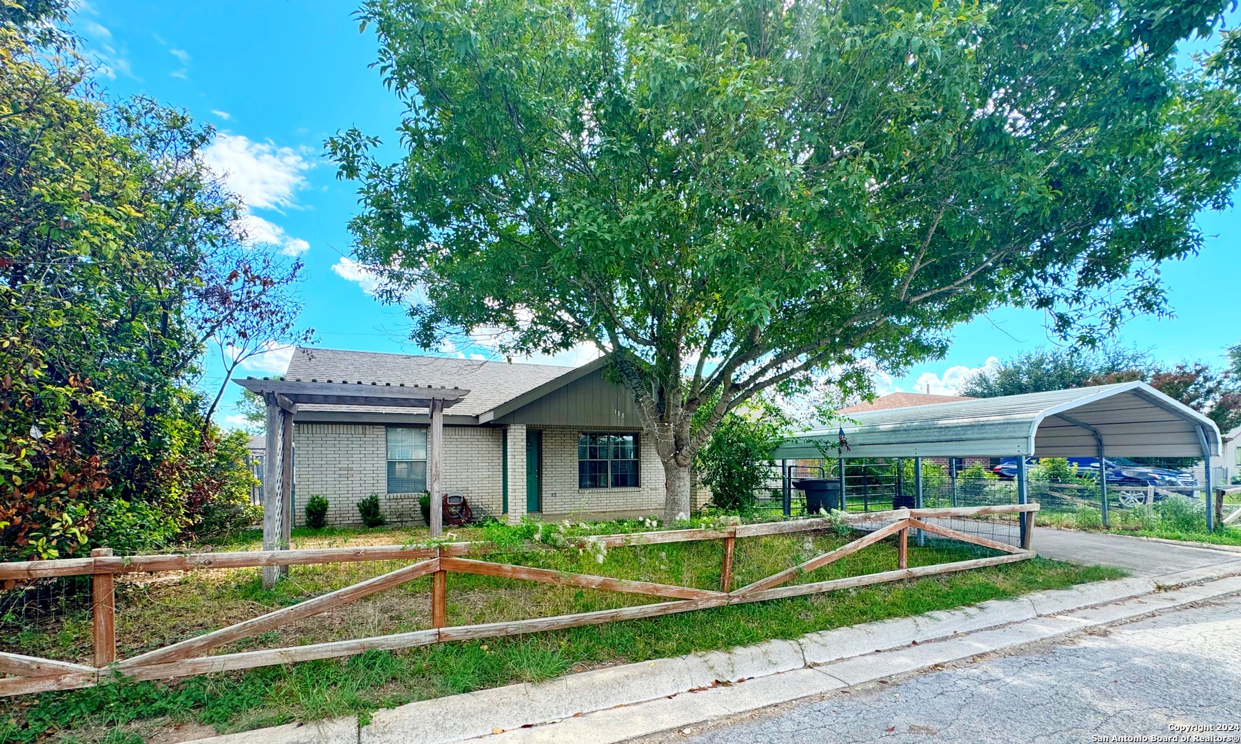 a view of house with a big yard and large trees