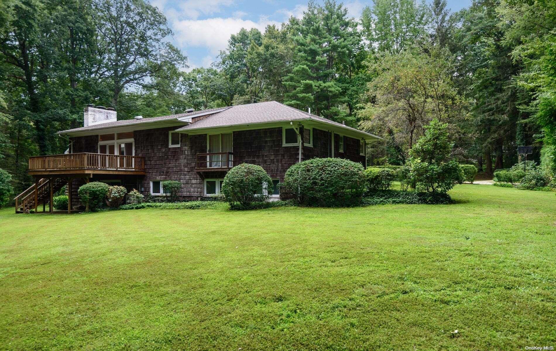 a backyard of a house with plants and large tree