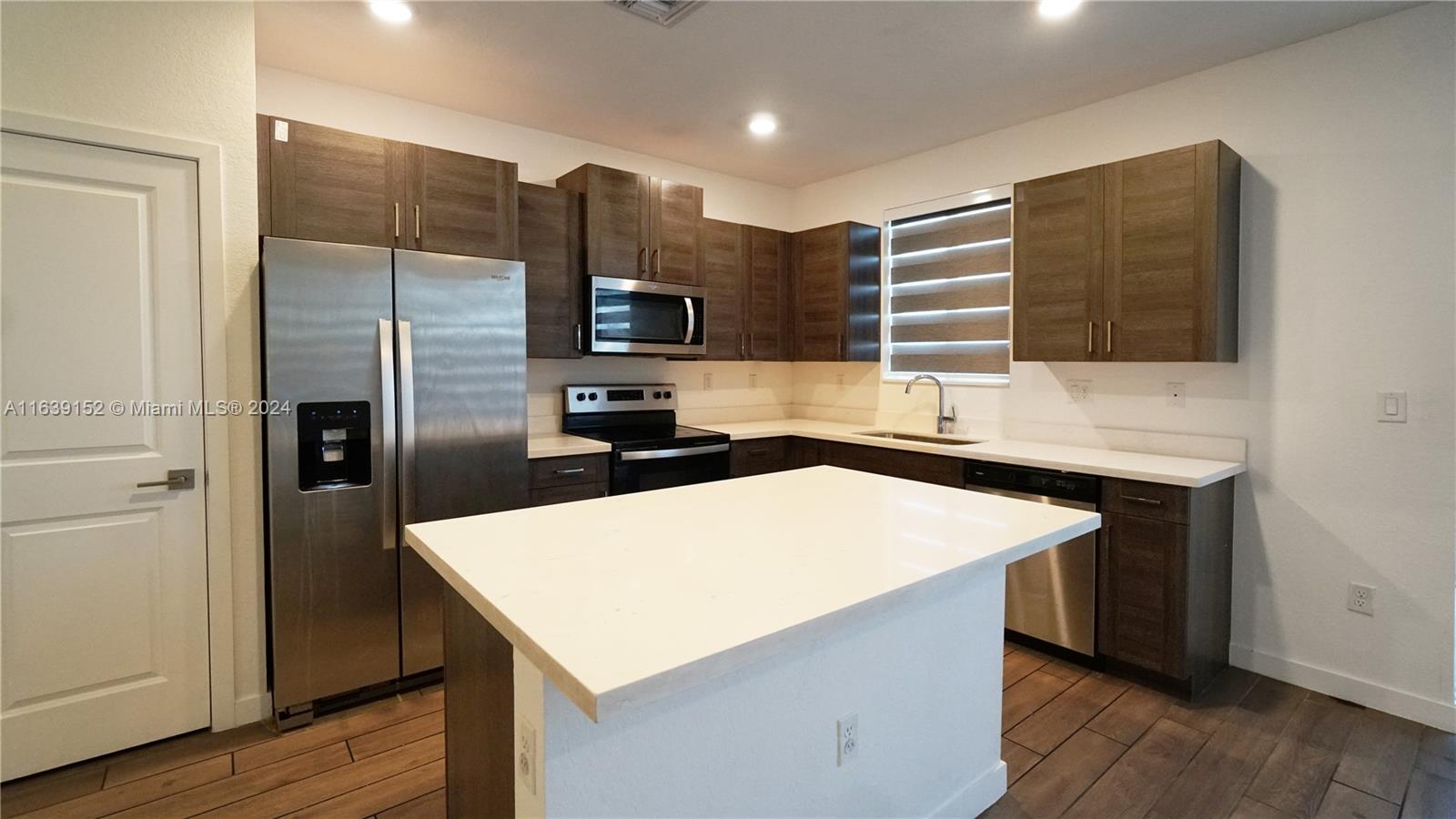 a kitchen with stainless steel appliances a refrigerator sink and microwave