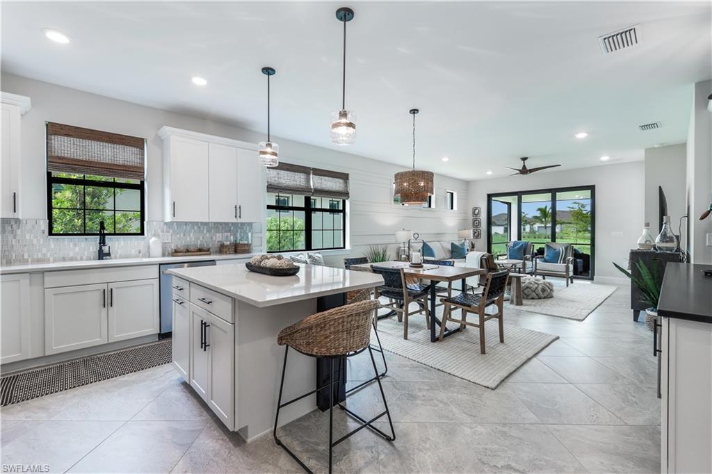 a kitchen with a dining table chairs sink and white cabinets