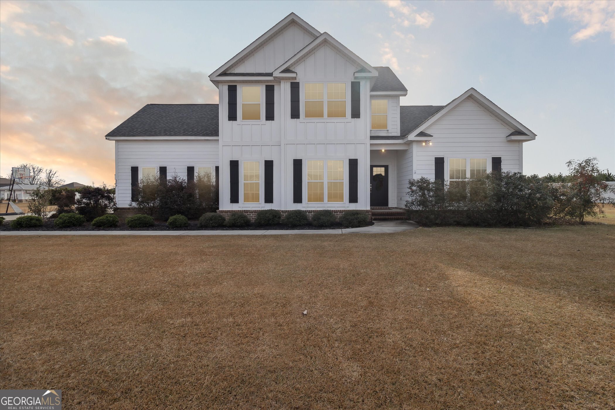 a front view of house with yard and trees in the background