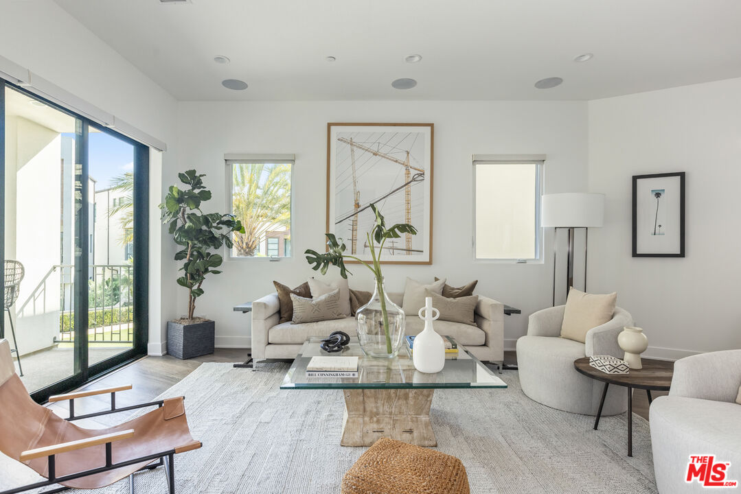 a living room with furniture large window and wooden floor