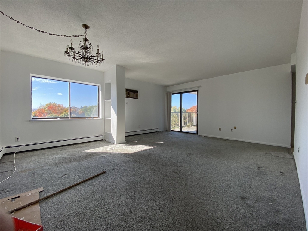 a view of a livingroom with a chandelier fan and windows