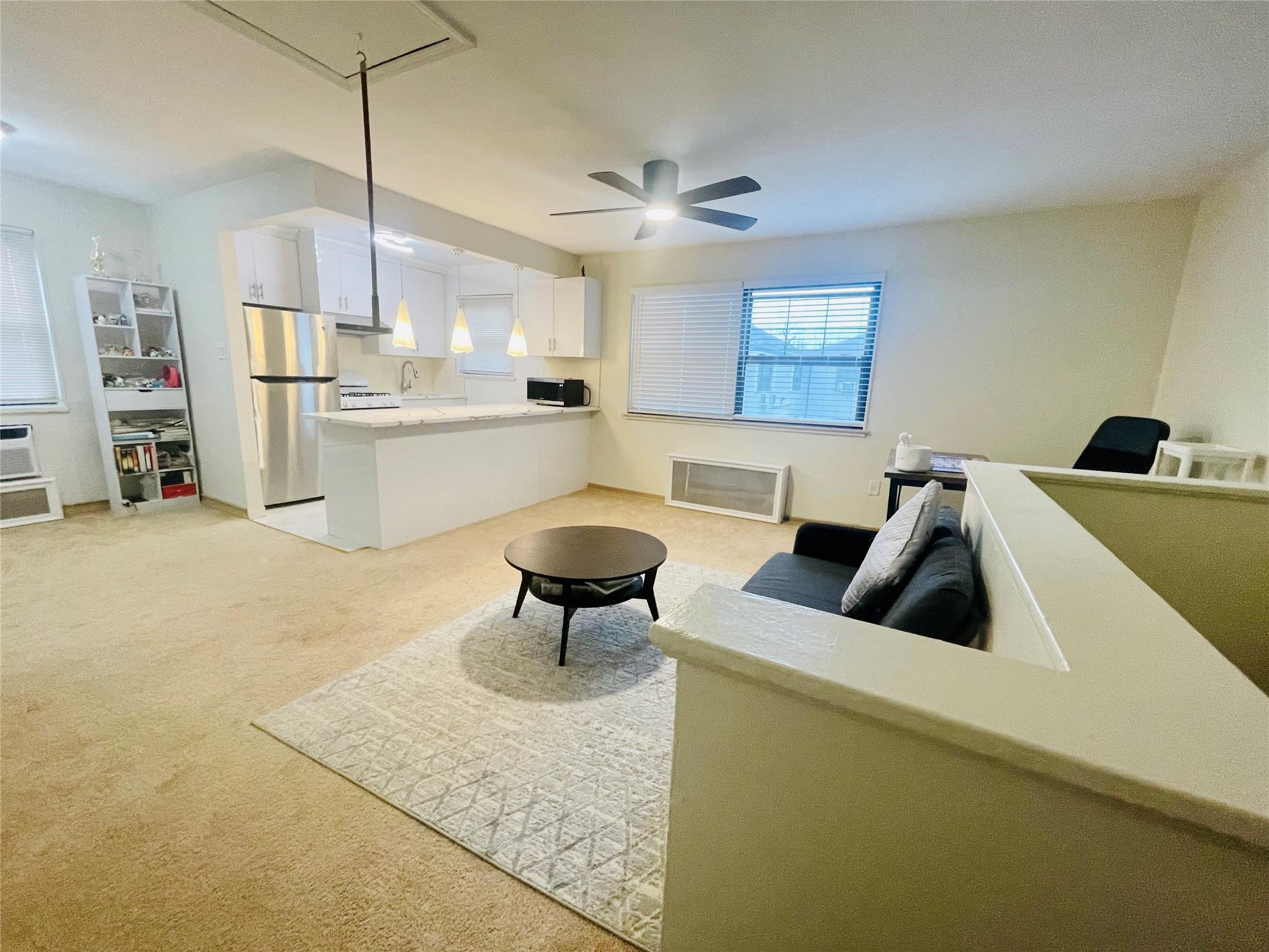 Living room with ceiling fan, sink, and light carpet