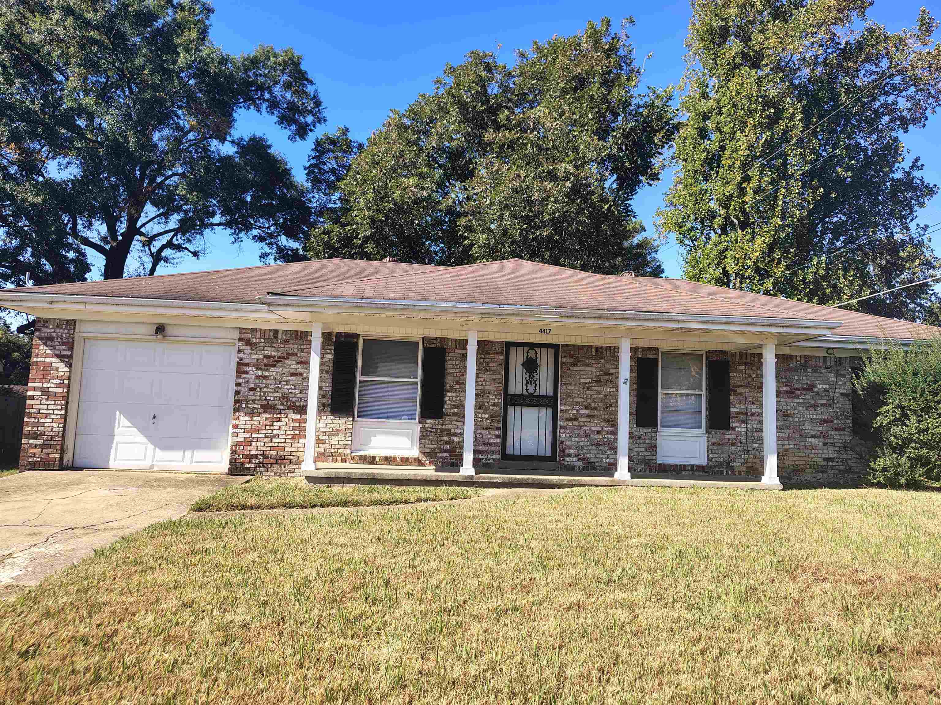 Ranch-style house featuring a front yard, a garage, and a porch