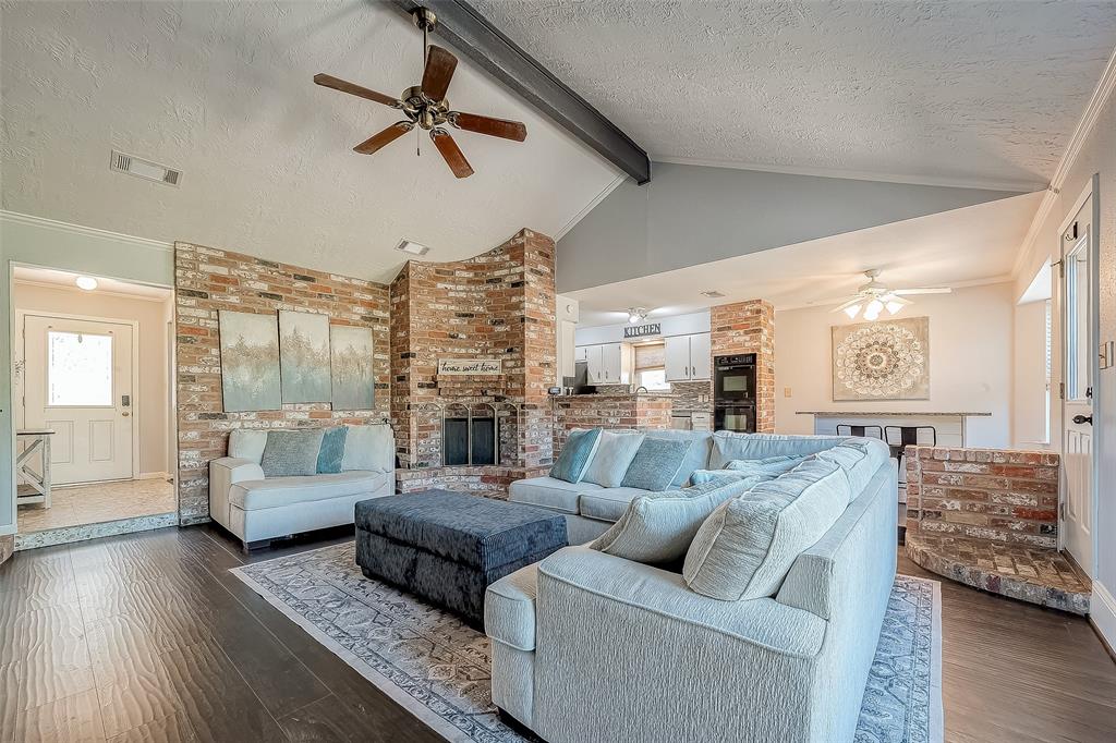 This expansive living area boasts soaring vaulted ceilings, which enhance the room’s sense of openness and light. A contemporary ceiling fan hangs from the high ceiling, offering both style and comfort by keeping the space cool.